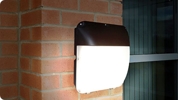 led wall pack illuminated at night against a red brick wall